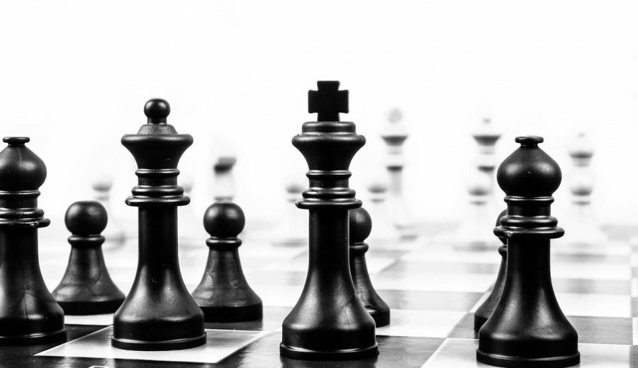 云顶虾神阵容搭配示意图：棋盘中央一名主C输出棋子被前排两名坦克棋子护住，两侧副C待命，界面以青绿色高亮显示羁绊加成